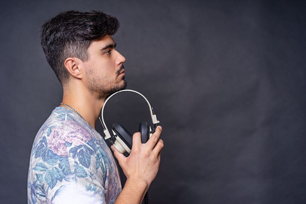 Homme de profil tenant un casque audio pour écouter de la musique