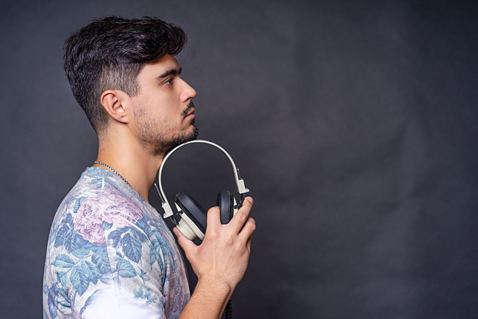 Homme de profil tenant un casque audio pour écouter de la musique